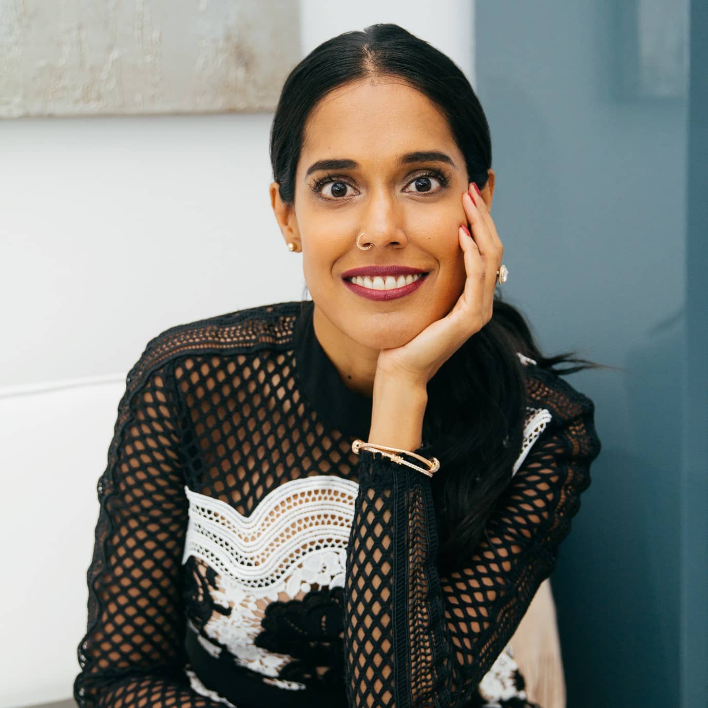 Ritu Bhasin wearing a white and black top, with her chin resting in her hand